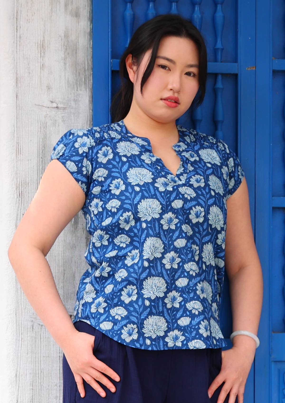 Model wears cotton blue floral top with ruched detail on the front of the shoulders