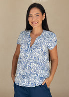 woman wearing a white based blue floral print, 100% cotton top.