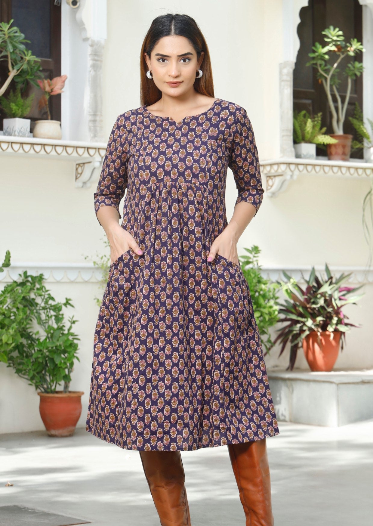Model wears a knee length cotton dress with 3/4 sleeves, round neckline and pockets.
