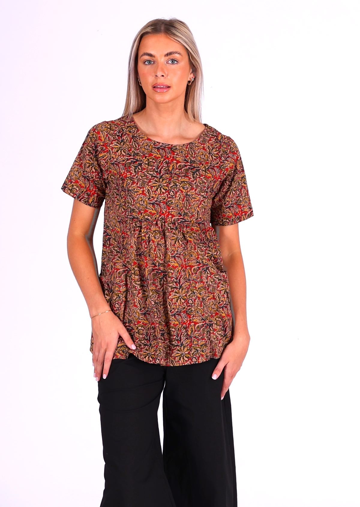 woman with blond hair wearing long cotton top Indian print in earthy tones over black cotton pants