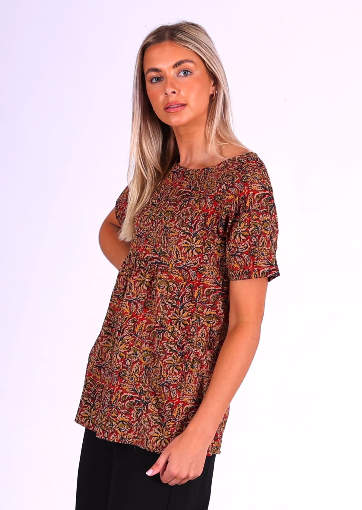 woman with blond hair wearing long cotton top Indian print in earthy tones side view