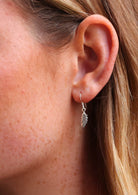 Close up of sterling silver earring  of a small feather with etched detail