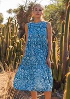 Woman in blue 100% cotton floral dress with hand in pocket