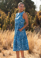 Woman in blue 100% cotton floral dress with hand in pocket in field of cacti