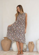 Woman flaunts 100 percent cotton relaxed fit sleeveless dress with high round neckline, pockets and tiered style.