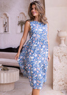 Woman wearing a midi length, blue floral sleeveless tiered dress in an elegant room 