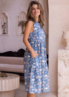 Woman standing sideways in a 100 percent cotton dusty blue floral sundress with pockets 