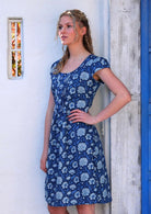 Woman stand with hand on hip in blue floral cotton knee length dress with scoop neckline and cap sleeves