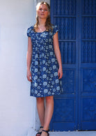 Model in scoop neck cotton knee length dress with cap sleeves in blue floral print