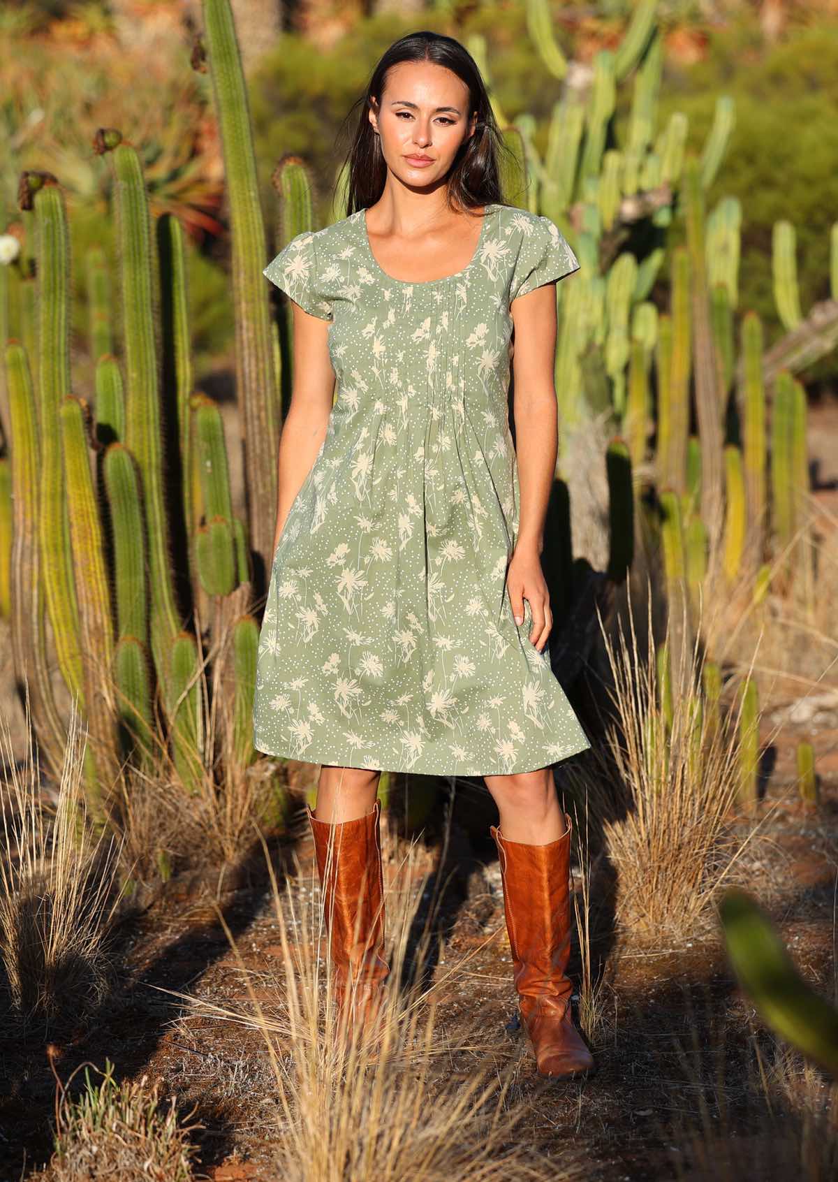 Woman wears cotton cap sleeved dress with a round neck and pin tucks across the bodice that lead to a slight A-line skirt