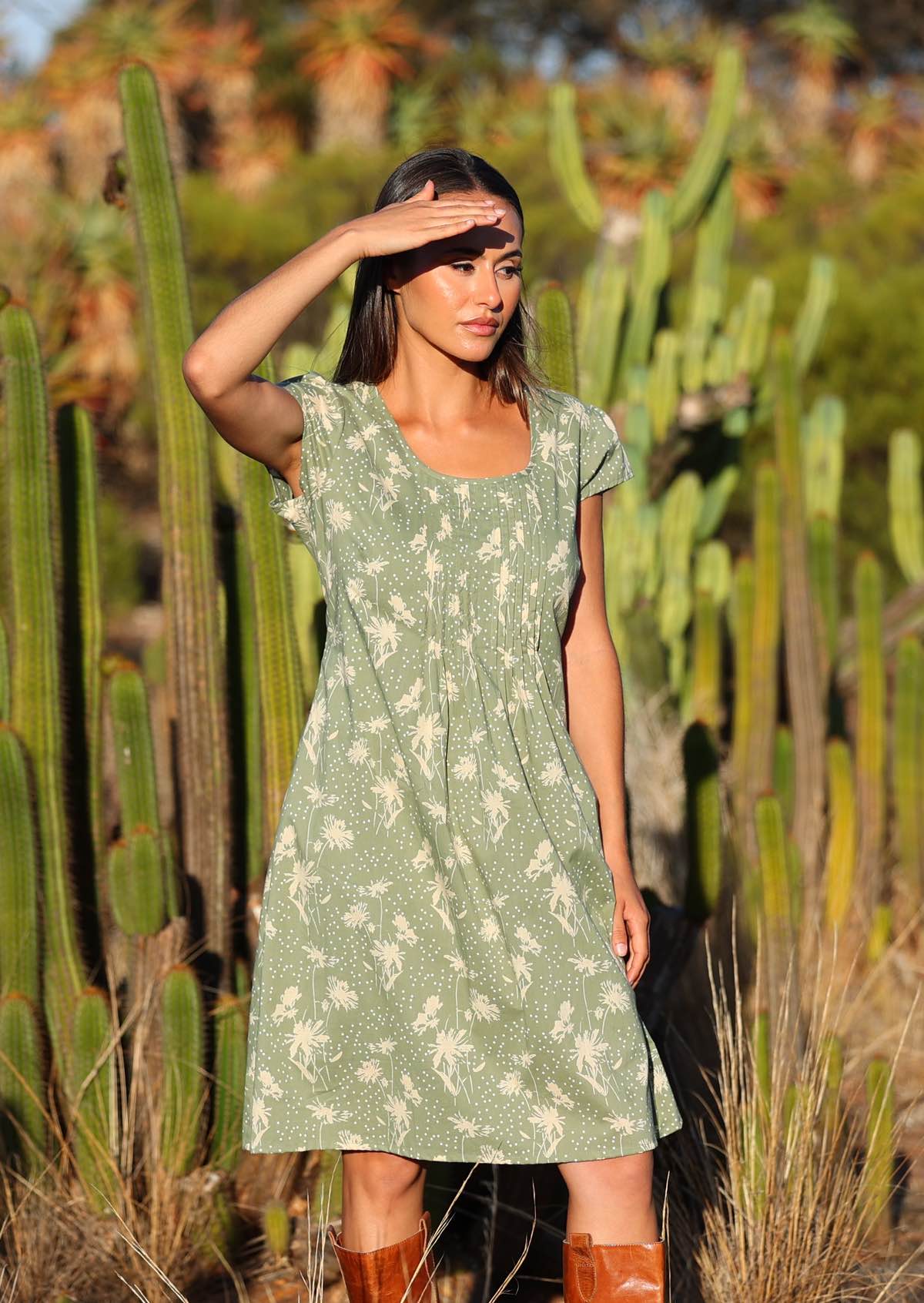 Model wears knee length cotton dress with cap sleeves and deep round neckline