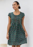 Woman wearing a green floral cotton dress against a white background