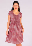 Model standing wearing 100 percent cotton short sleeve pleated sundress in dark terracotta