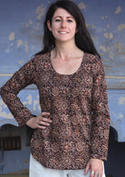 Woman with hand on hip wearing 100% cotton long sleeve top with tiny pleated details and round neck.