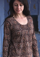 Woman wearing 100% cotton long sleeve top with tiny pleated details and round neck.