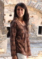 Model looking over her shoulder wearing 100% cotton long sleeve top with round neckline and tiny pleat detail from the center of the neckline.