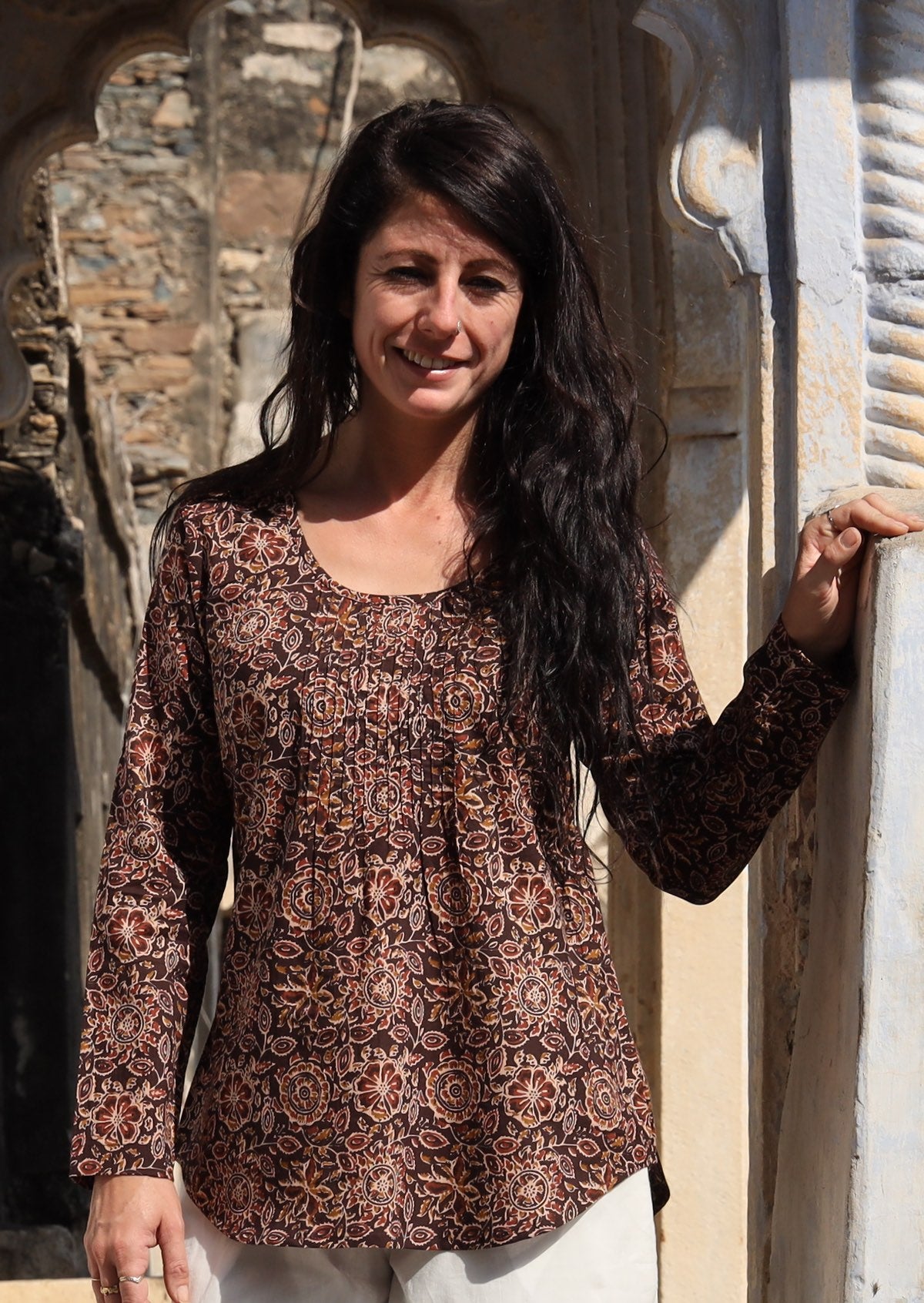 Model wearing 100% cotton long sleeve top with round neckline and tiny pleat detail at the neckline.