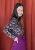 Women wears Dark purple based floral printed long sleeve top tucked in and paired with belt loop skirt in Plum.