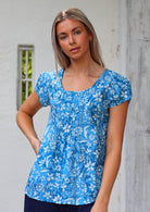 Woman wears relaxed fit cotton cap sleeved top in blue floral print