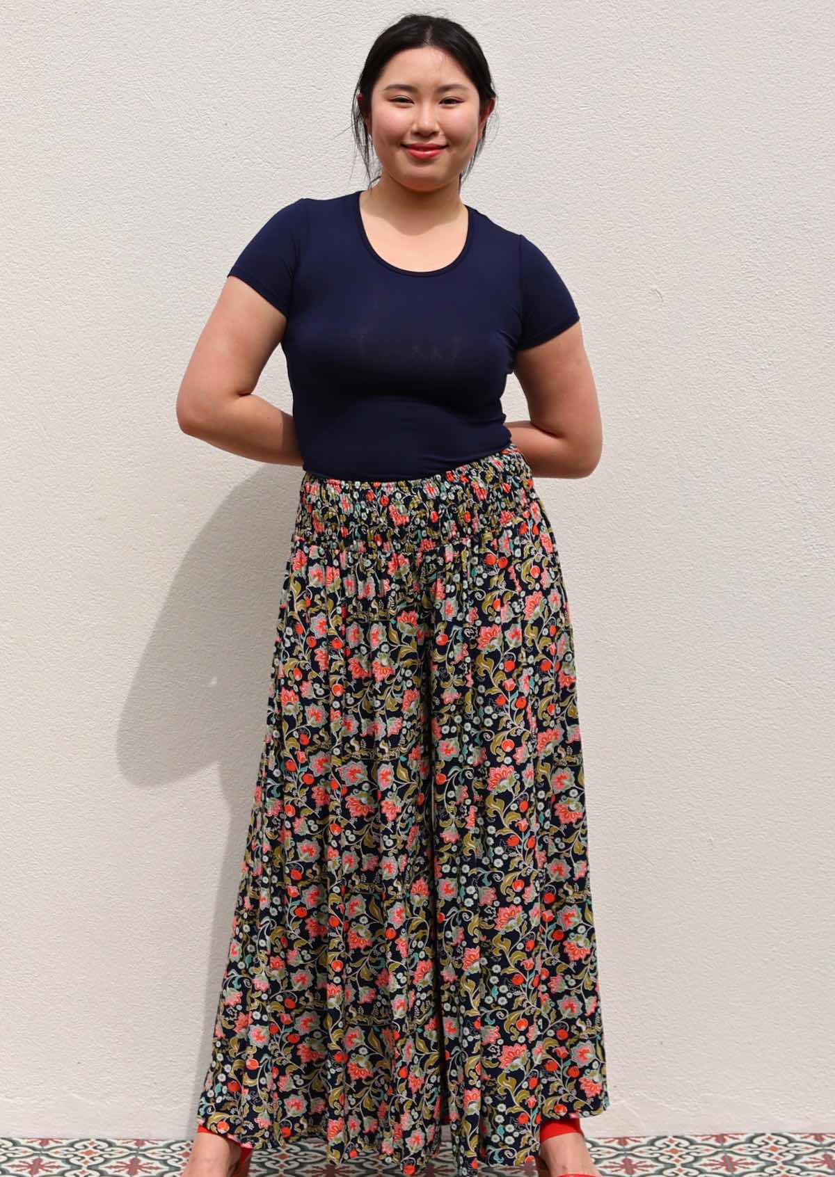 Model with hands behind back standing infront of white wall wearing rayon wide legged womens palazzo pant with elastic waist