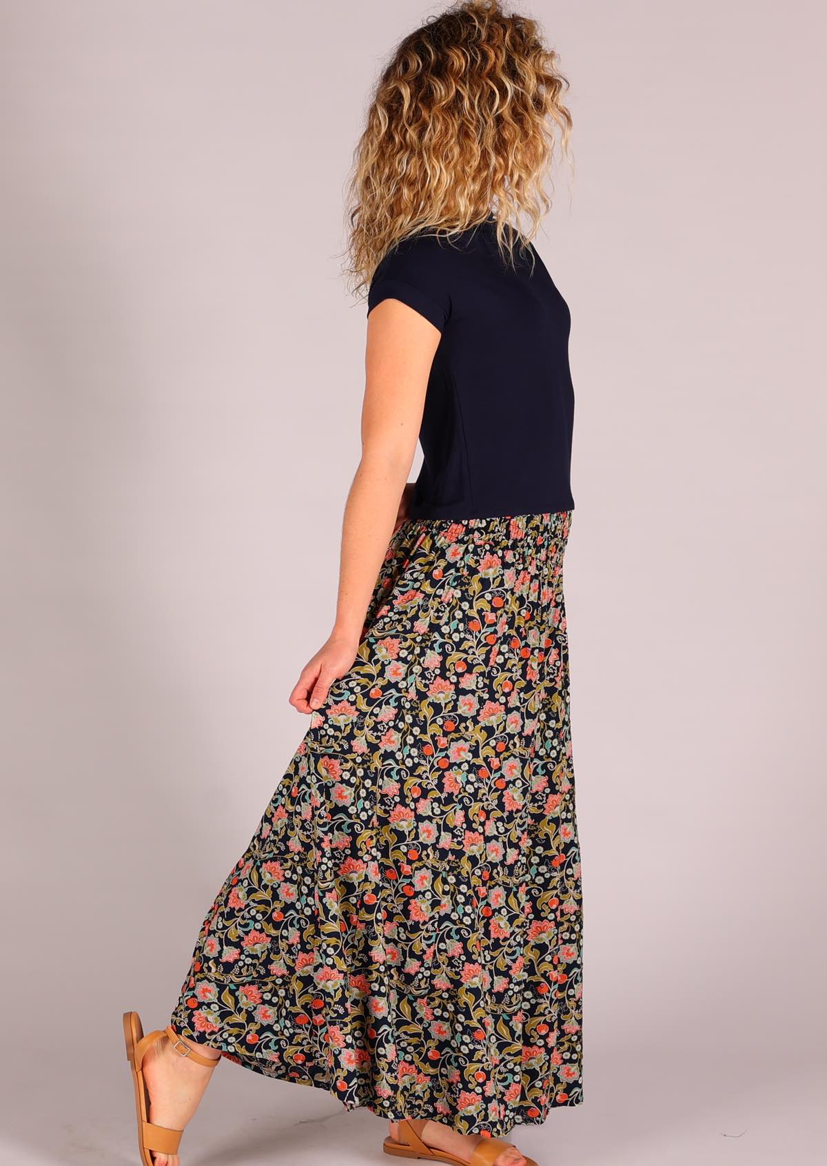 Model with hands behind back holding pant leg wearing rayon wide legged womens palazzo pant with elastic waist