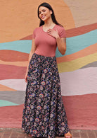 Woman wearing Indian print dark rayon wide leg pants with shirred waist band and pink t-shirt in front of sun mural