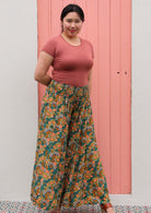 Woman in green floral wide legged floral pants with shirred elastic waist and pink scoop neck tee