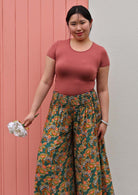 close up of Woman in green wide legged floral pants with shirred elastic waist and pink scoop neck tee