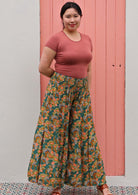 Woman in green wide legged floral pants with shirred elastic waist and pink scoop neck tee