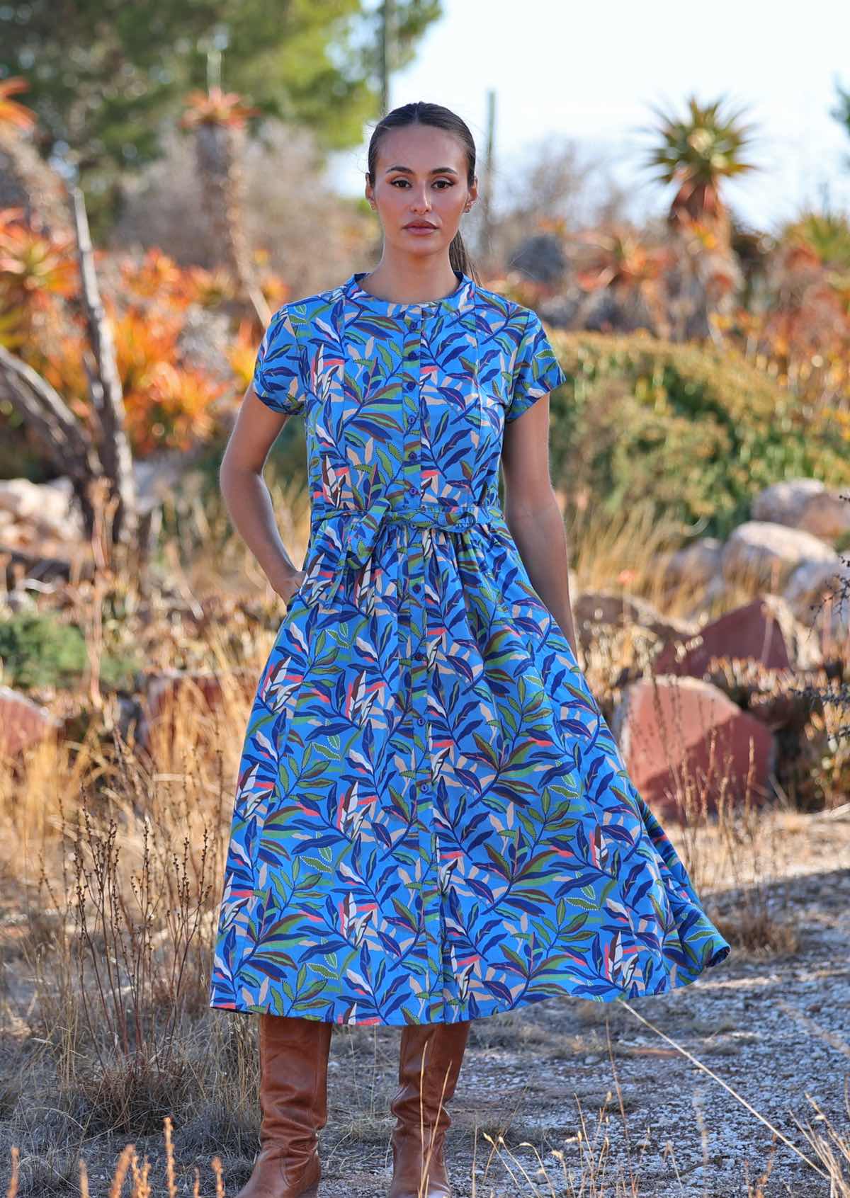 Woman standing in blue cotton leafy button down maxi dress with one hand in pocket 