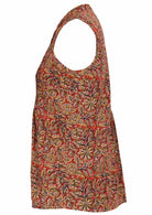 This side view shows a sleeveless blouse with a floral print, featuring a button-up collar, and pleats down the front. It’s fitted with a slight flare from the waist