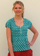 Model with one hand on hip wearing 100 percent cotton aqua top with small functional shell buttons 