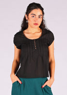 Model wears black scoop neck cotton top with central coconut buttons across bust