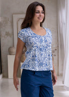 Woman wearing a white based blue floral print, 100% cotton top with white background.