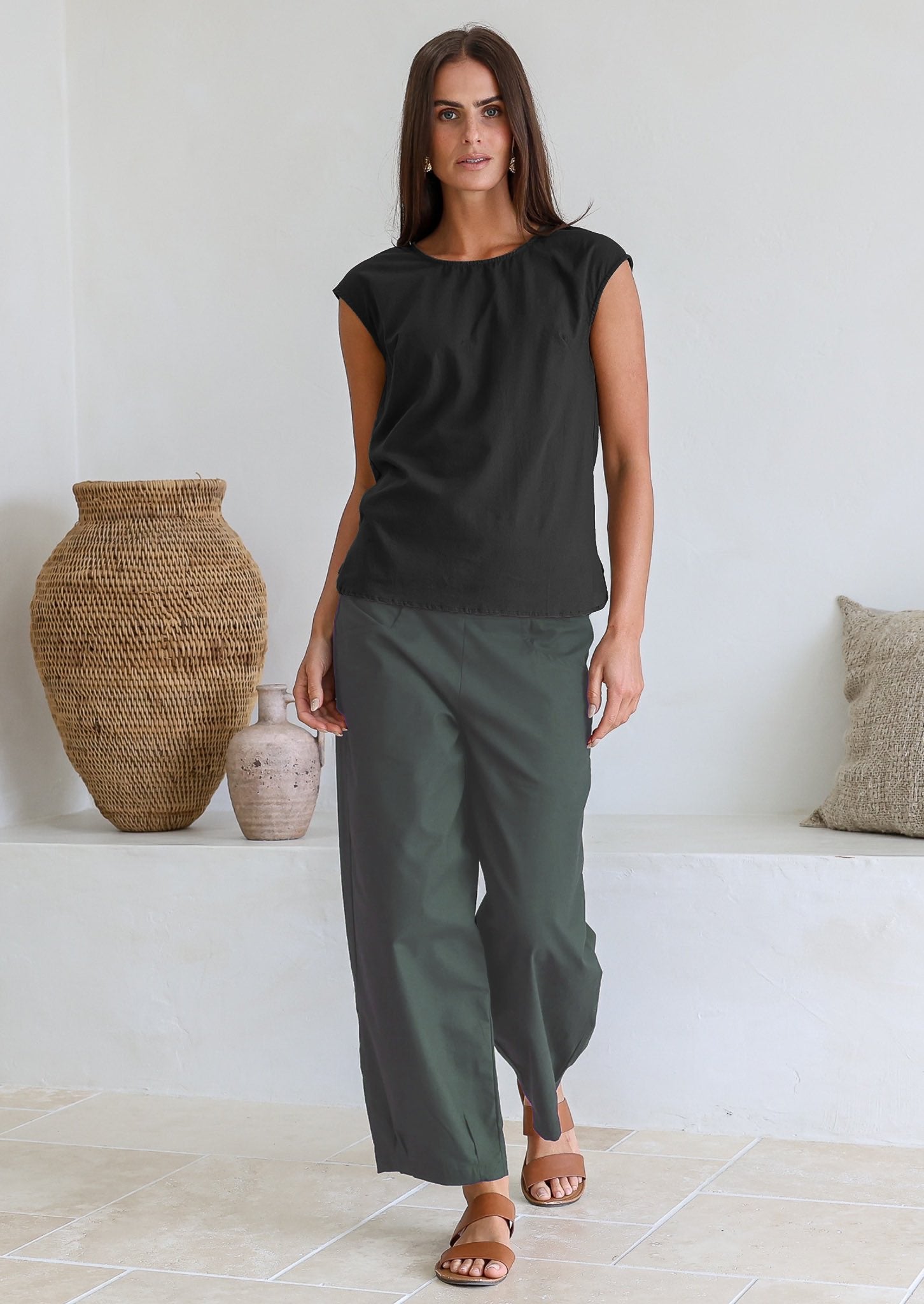 Woman wearing a black cotton sleeveless top paired with long green pants