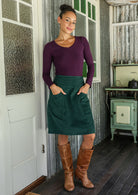 woman wearing a cotton corduroy skirt in luxurious, deep blue-green with both hands in pockets