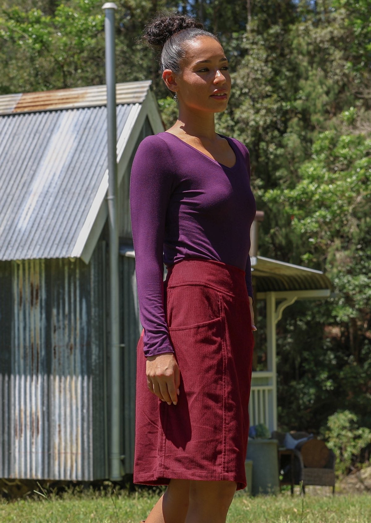 Woman stands sideways wearing a cotton corduroy skirt and basic top 