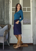 Woman stands sideways wearing a  cotton corduroy skirt and basic top with one hand in her pocket