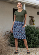 Woman wearing a basic top and floral  cotton skirt in navy with A-line shape, piped detailing and pockets.