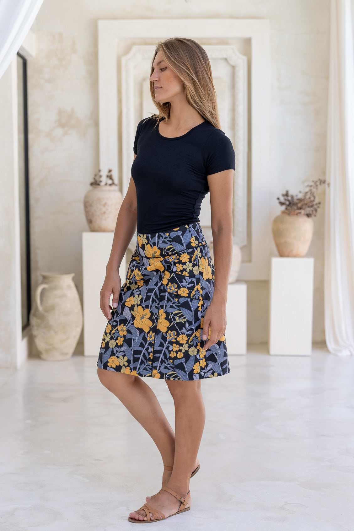 Woman posing in a 100% cotton retro floral skirt in black with side zipper, piped detailing at waist and pockets.