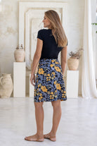 Model wears cotton above knee length A-line skirt in black based yellow and grey floral print, paired with a basic black top.
