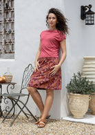 Woman leans on wall wearing a Japanese style floral above knee length cotton skirt in warm toned