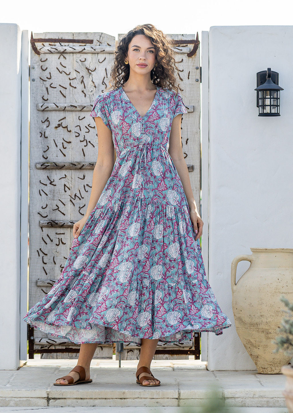 Woman stands in rayon maxi dress with tulip sleeves, V-neckline and buttoned bodice