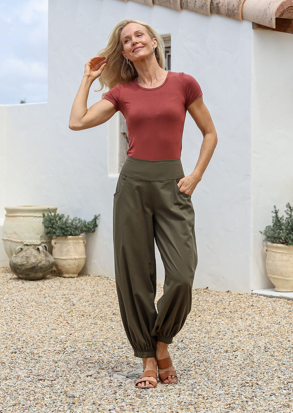 Woman in a terracotta basic top and green cotton pants with wide flat front waistband shirred at the back and cuffed ankles