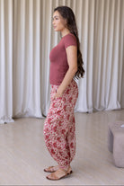 Woman stands sideways wearing floral cotton wide leg pants with buttoned ankle paired with pink basic top