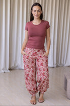 Woman wearing a basic top and gentle cream based cotton floral pants, with her hand in pocket