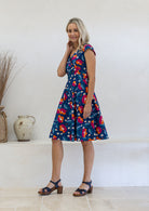 Model posing sideways in a beautiful 100% cotton dress with royal blue based floral print