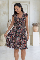 Model holds one side of the 100% cotton retro style Indian floral print dress with cap sleeves, pockets and crossover bodice.