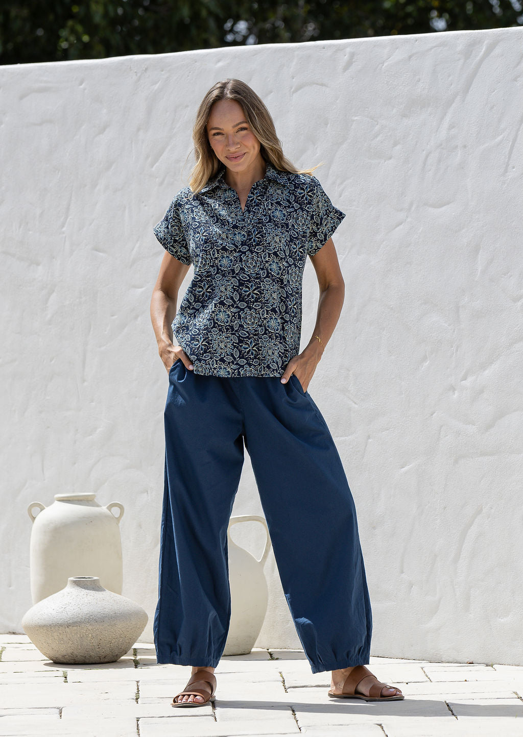 Woman poses in relaxed fit cotton short sleeve top with rolled cuffs sleeves, collar and V neckline.
