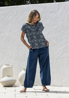 Woman wearing a navy blue based relaxed fit, shirt style floral cotton top with plain pants.